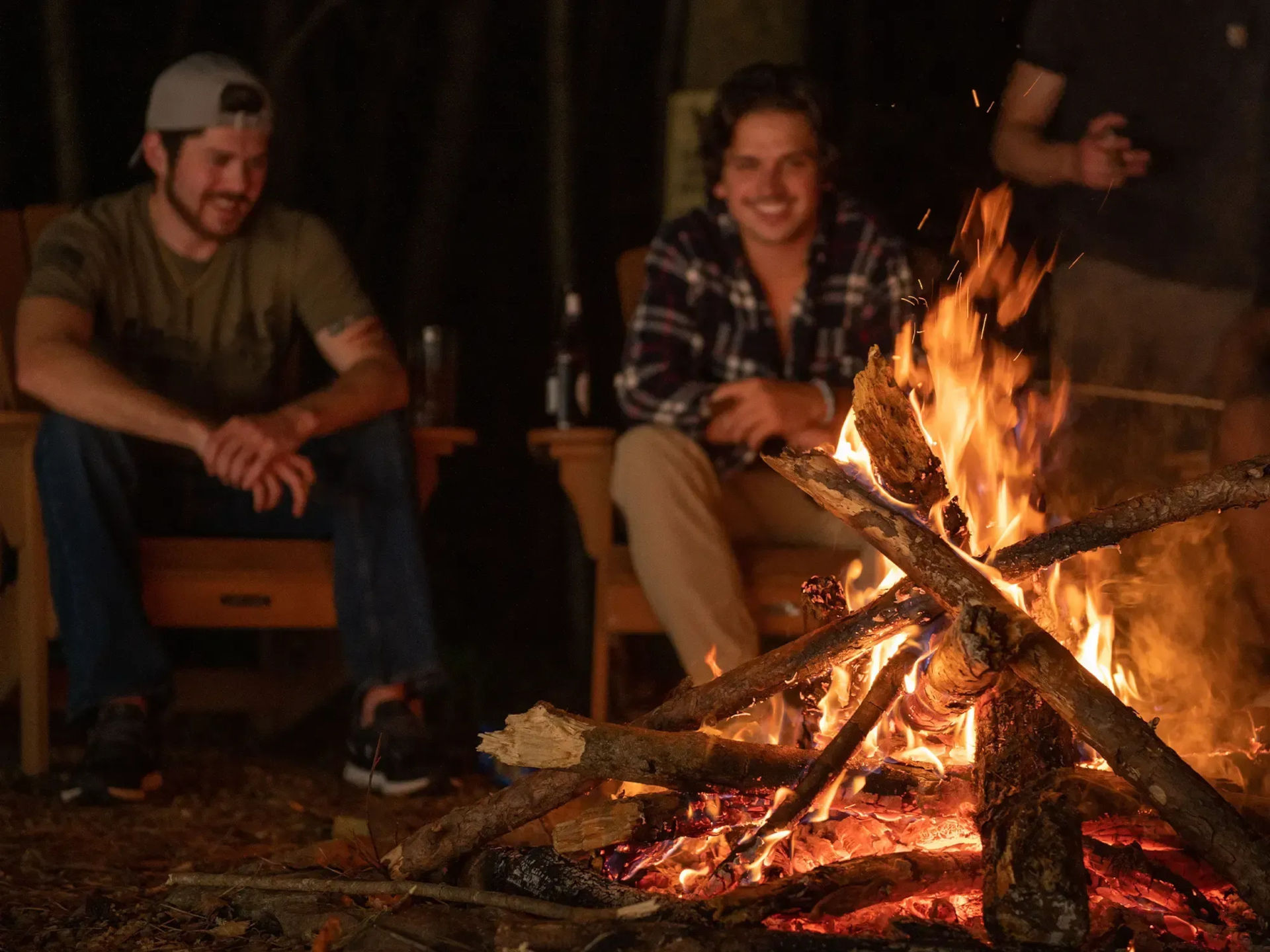 group of men sitting around a fire pit at night