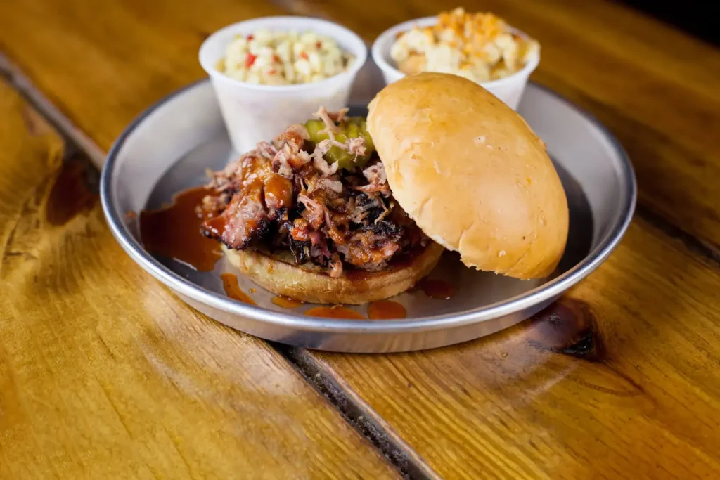 bbq sandwich and coleslaw on a wood table at edley's bar-b-que.