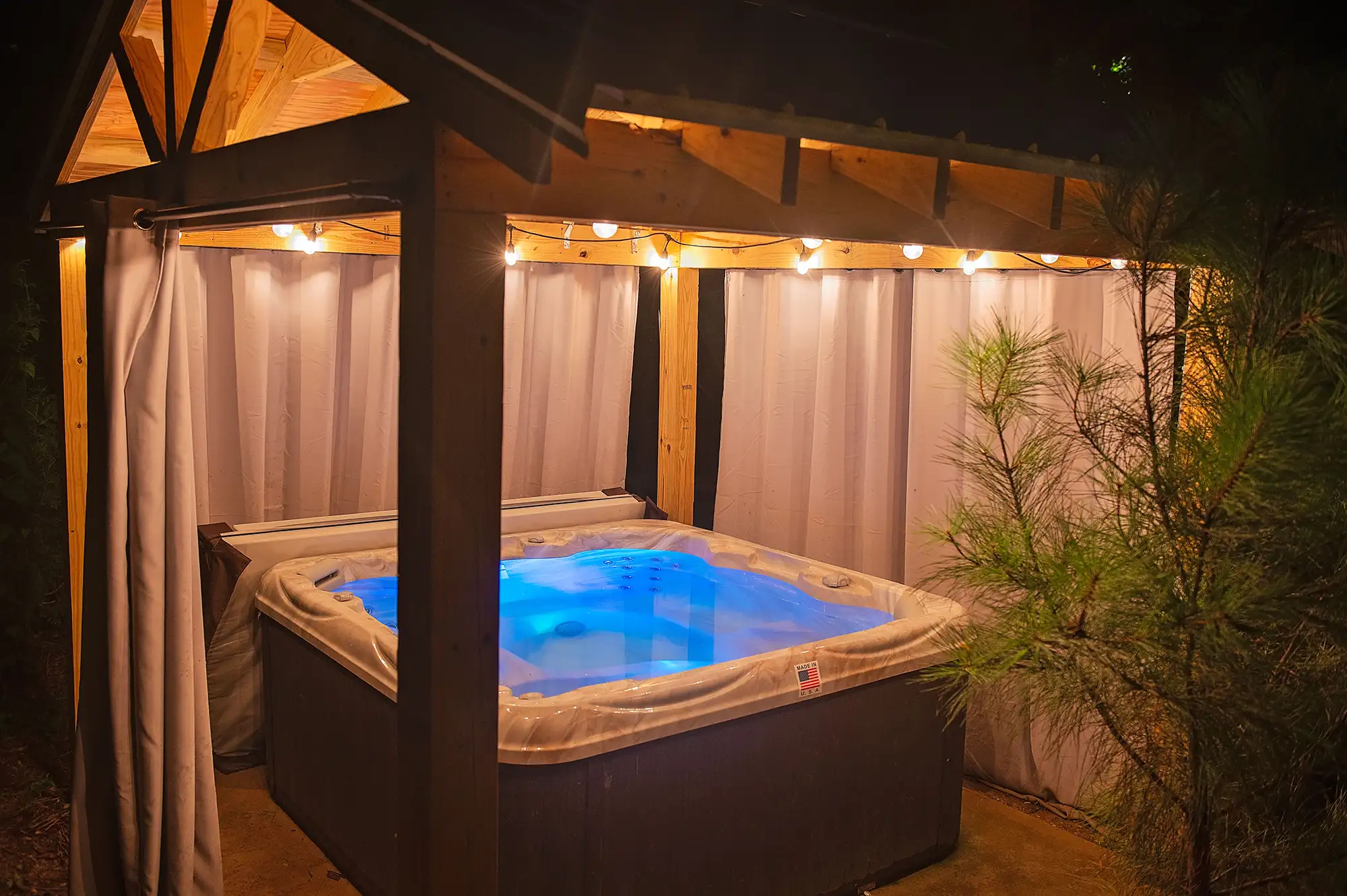 Hot tub at night under a cabana strung with twinkle lights