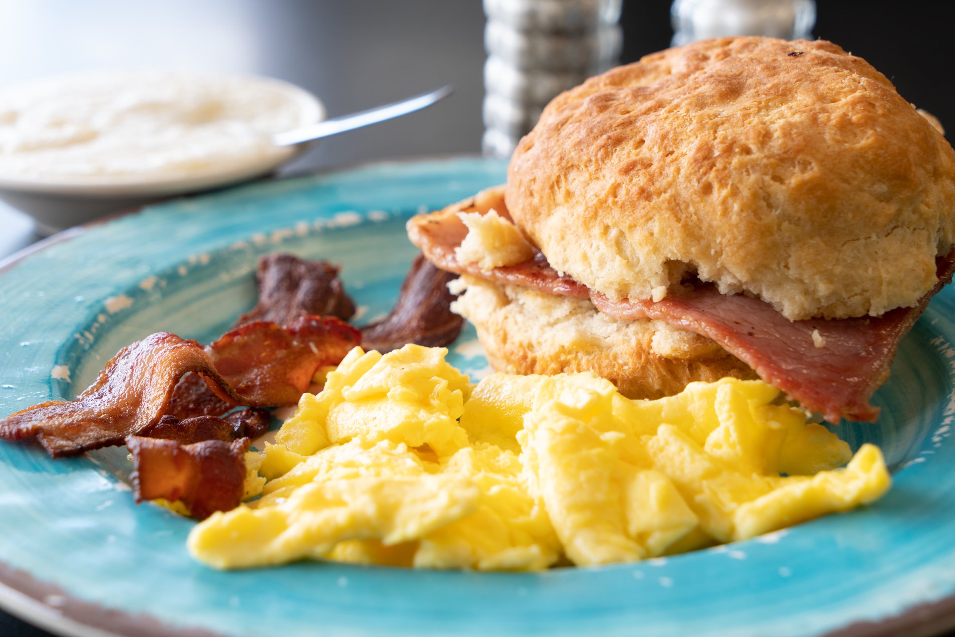 bacon, biscuit and eggs on a blue plate