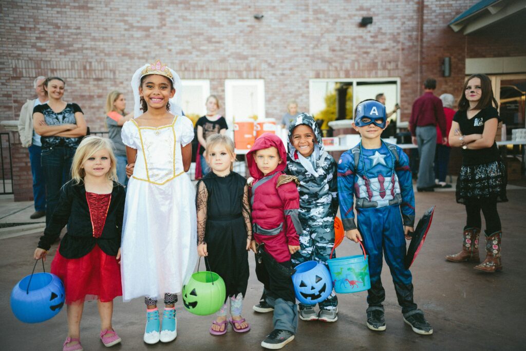 Kids standing smiling in various Halloween costumes