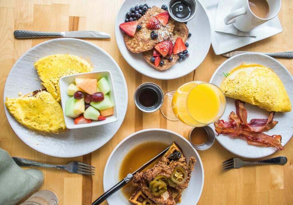 Flatlay of breakfast table featuring pancakes, waffles, omelettes, juice and coffee