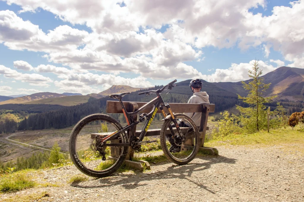 Mountain biker sitting on a bench with his bike leaned against it in Cherokee National Forest