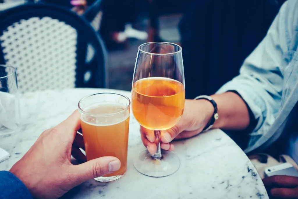 Two people holding glasses of Fall-themed drinks, fall beer, fall cider