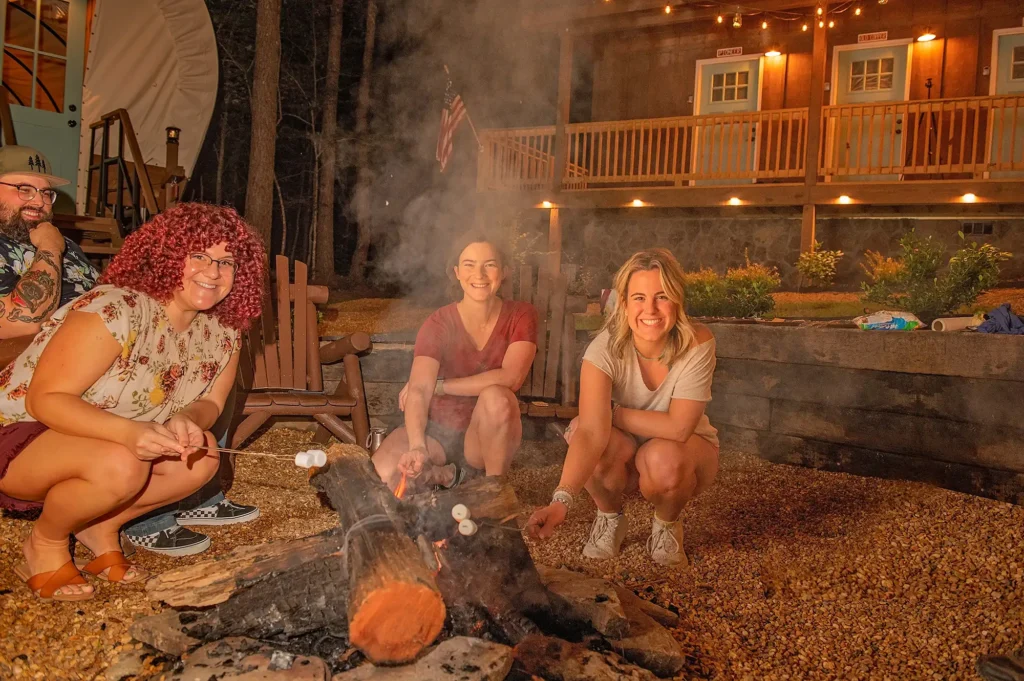 girls roasting marshmallows while covered wagon camping