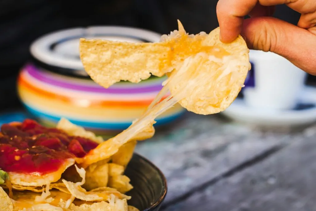 Hand pulling a cheesy nacho chip for a great camping meal