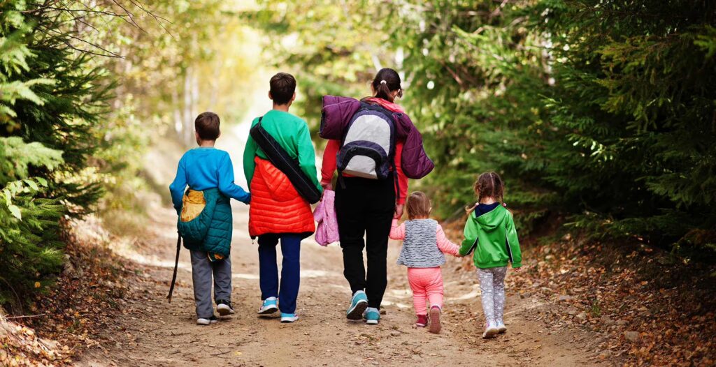 Back of mother with 4 children hiking in the woods