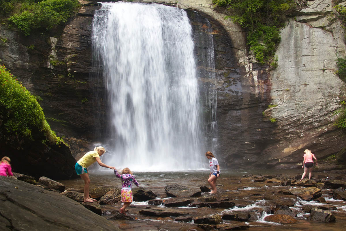Visitors standing at the base of Looking Glass Falls in Pisgah National Forest