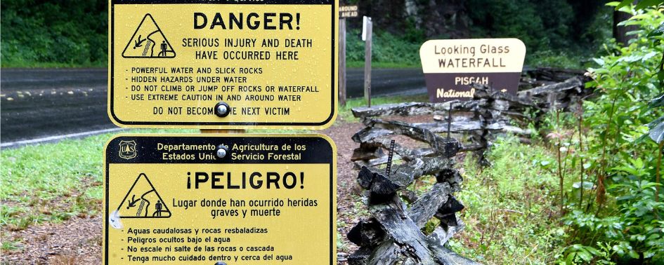 Warning signs at Looking Glass Falls in Pisgah National Forest cautioning visitors about dangerous waterfall conditions