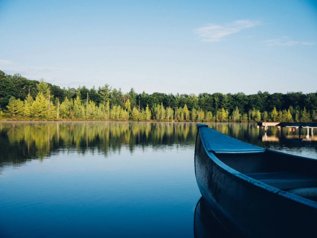 Canoe resting on a calm lake surrounded by trees and forest