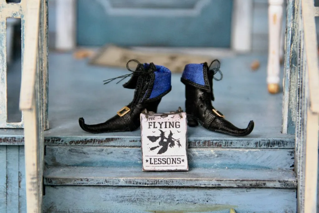 Witch shoes on a porch step beside a ‘Flying Lessons’ sign, symbolizing Halloween decor and festive fall events