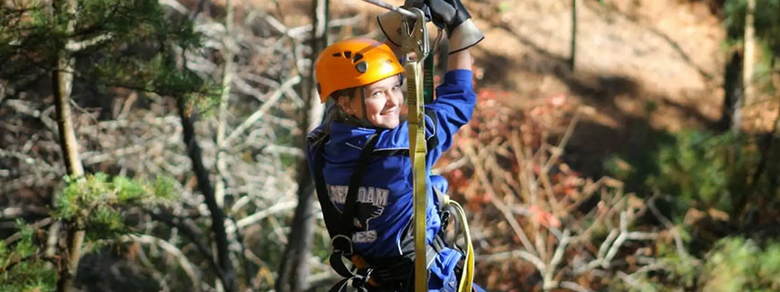 Zipline rider soaring through forest canopy near the Ocoee River