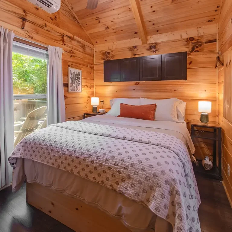 Cozy bedroom inside a rustic tiny cabin with wood walls and a comfortable bed
