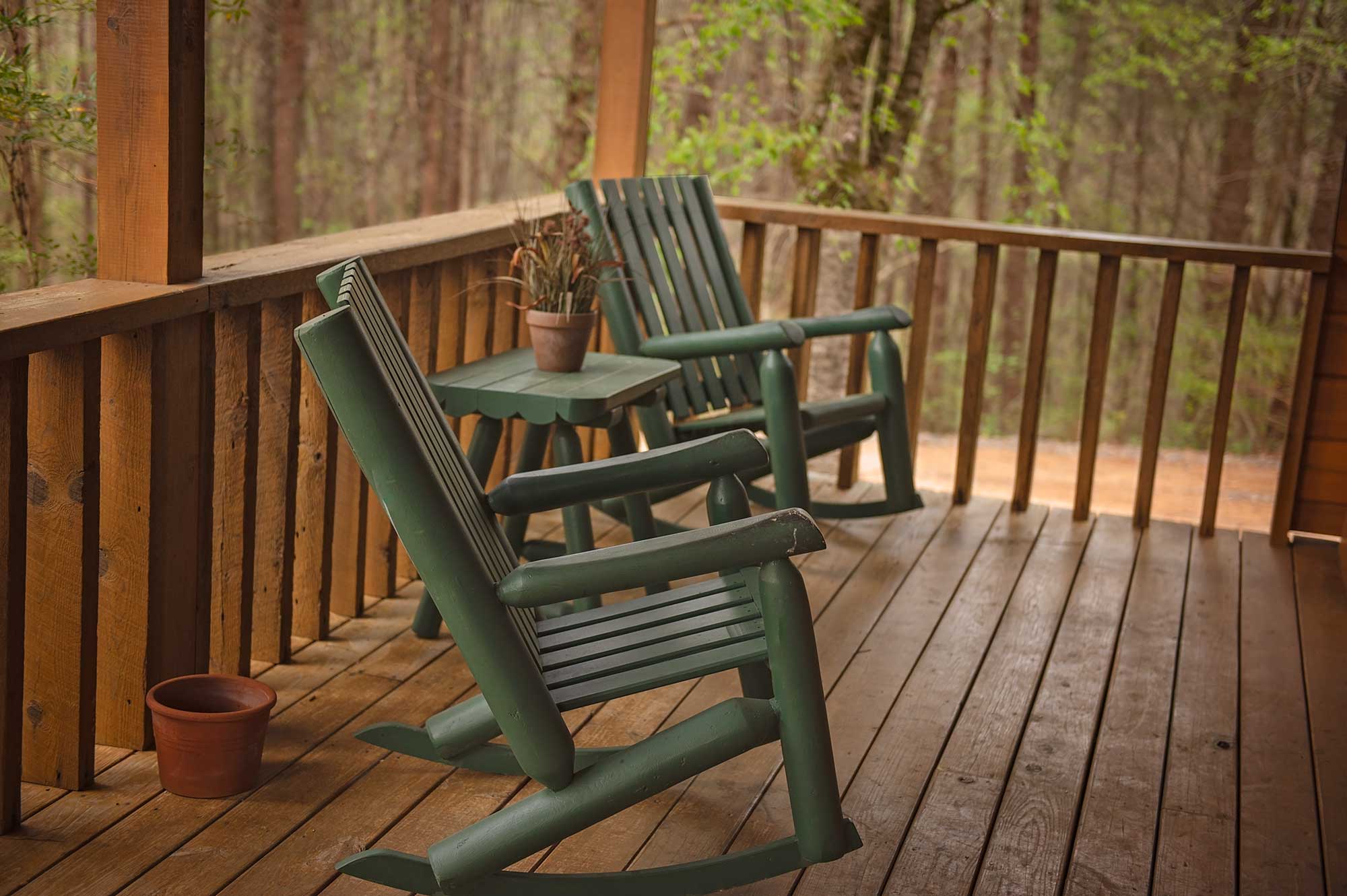 two green rocking chairs on a cabin porch